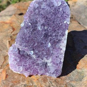 Amethyst statement piece with rich purple crystal formations and natural purple tones displayed on a rock.