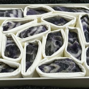 Raw Dream Amethyst crystal held in a hand, showing its natural purple tones and unique crystal formations.
